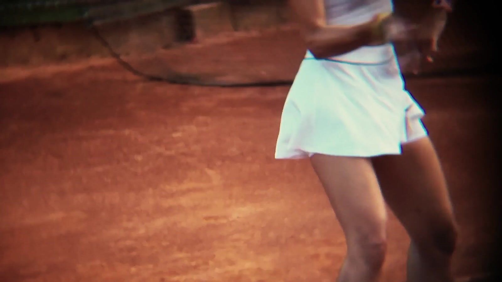 A woman seen from above on a clay tennis court scattered with tennis balls (1/8)