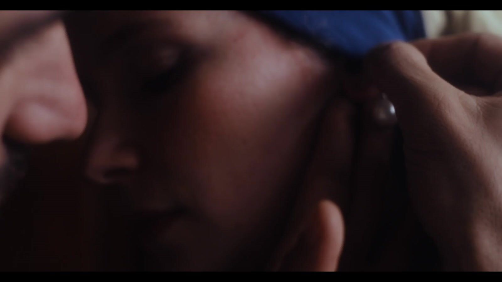 A man and a woman in a dim room, she wears a blue headscarf and a pearl earring (5/8)